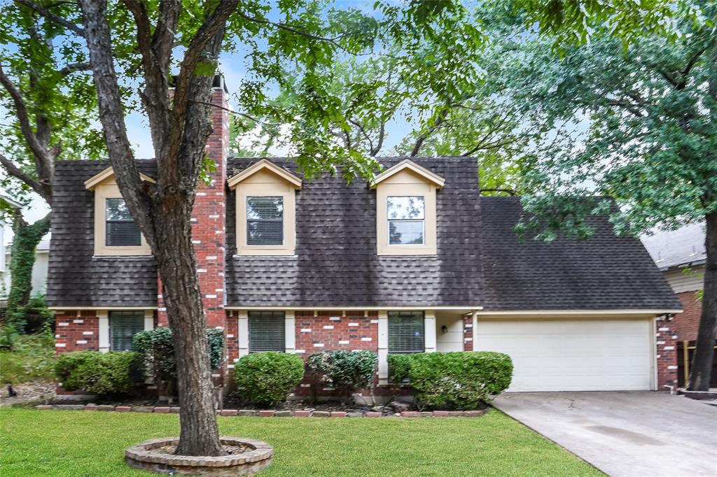 a front view of a house with a yard and trees