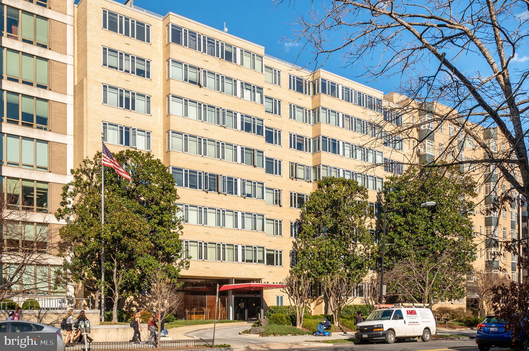 a front view of a building with lot of cars and trees