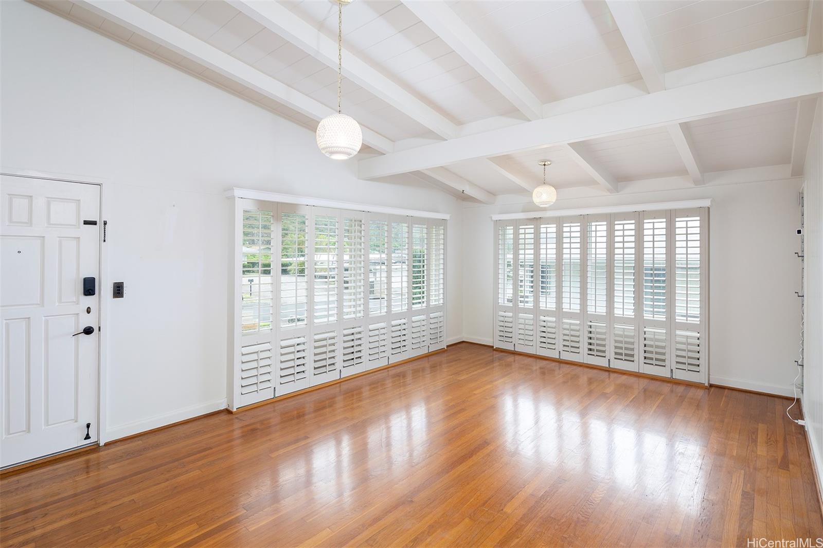 a view of an empty room with wooden floor and a window