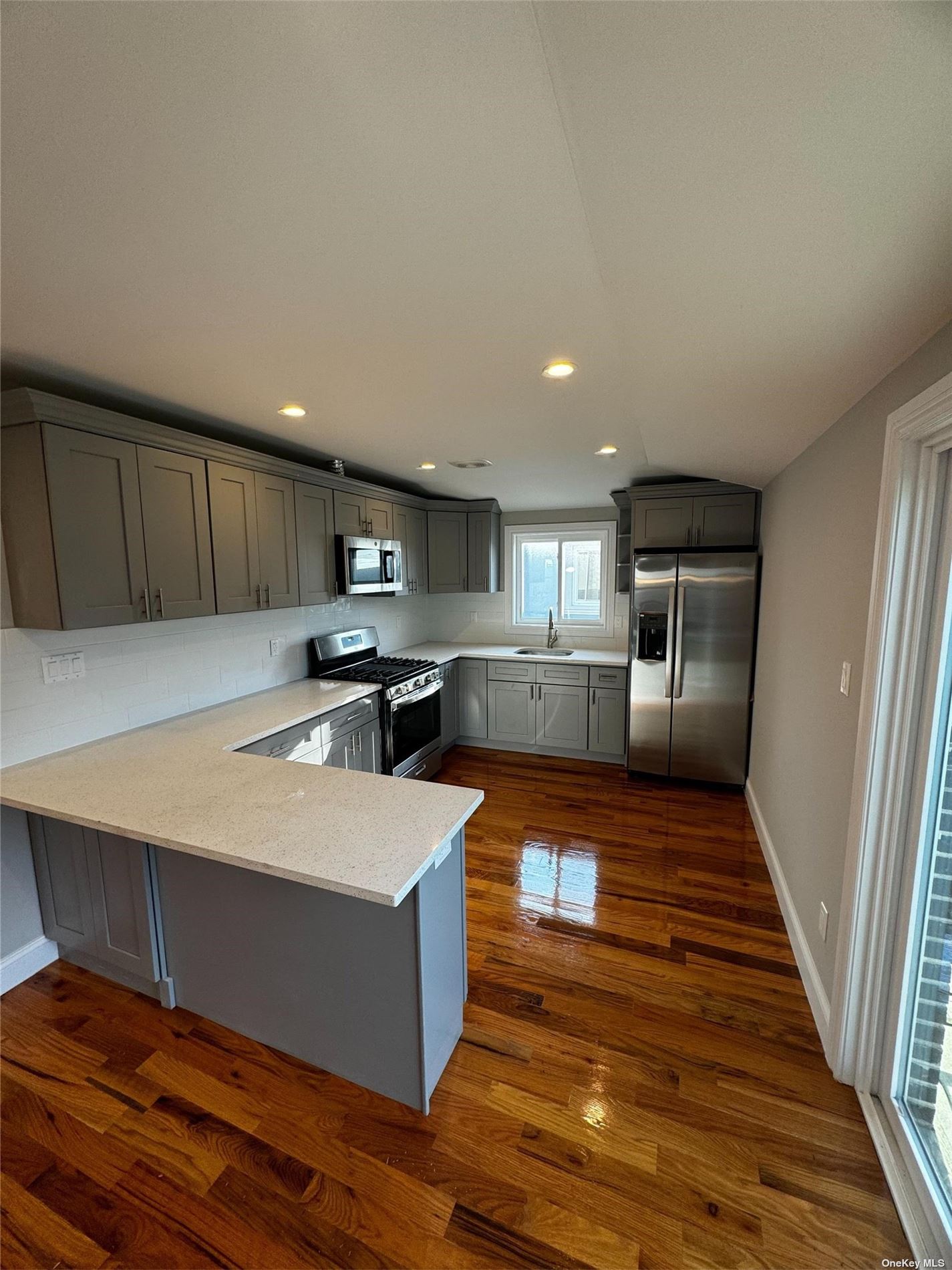 a large kitchen with wooden floors stainless steel appliances and a fireplace