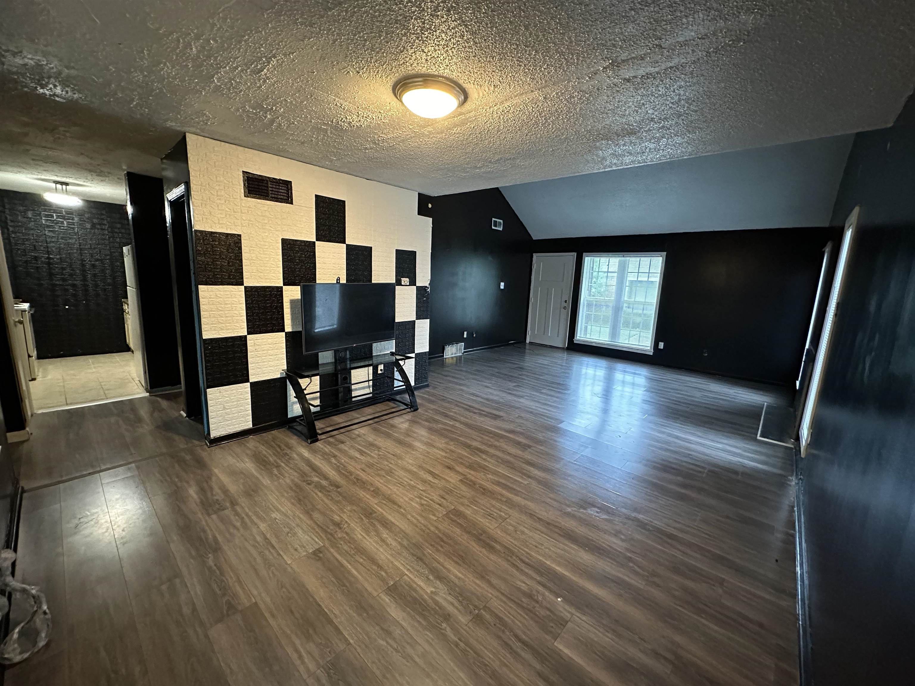 an empty room with wooden floor and windows