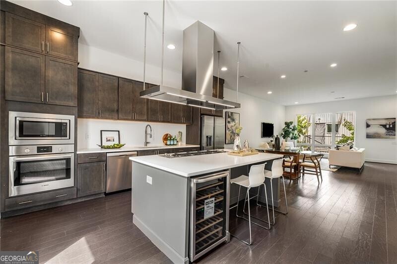 a kitchen with stainless steel appliances a table chairs wooden floors and a view of living room