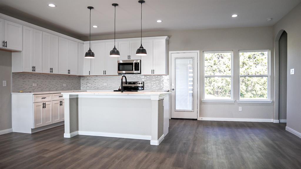 a kitchen with kitchen island white cabinets stainless steel appliances a sink and wooden floor