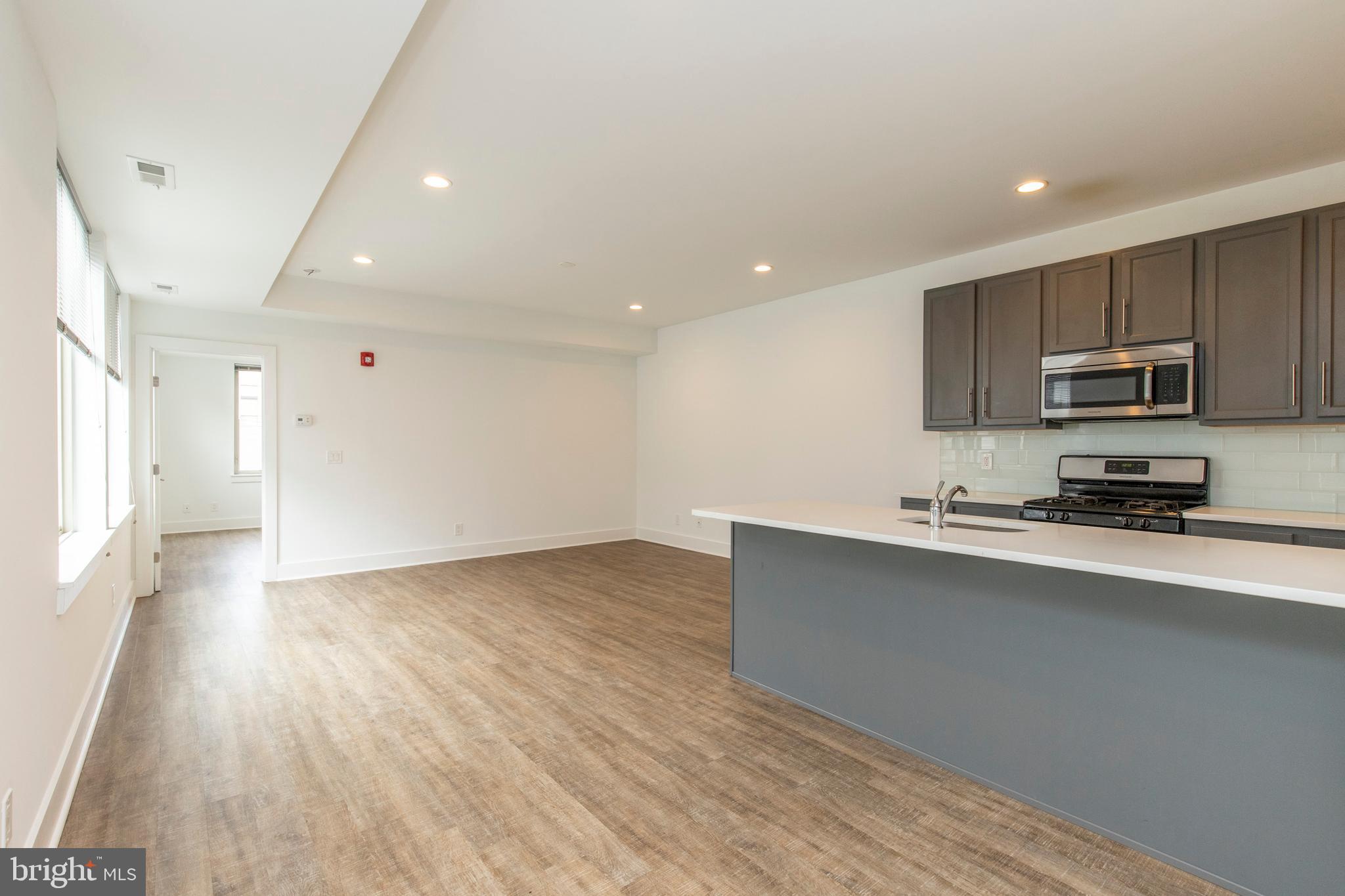 a kitchen with stainless steel appliances a sink cabinets and wooden floor