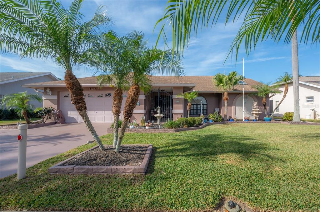 a view of a house with a yard and palm trees