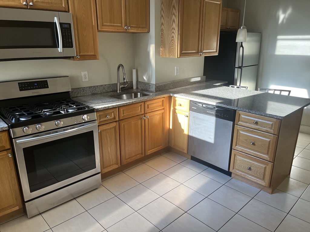 a kitchen with granite countertop a sink stove and cabinets