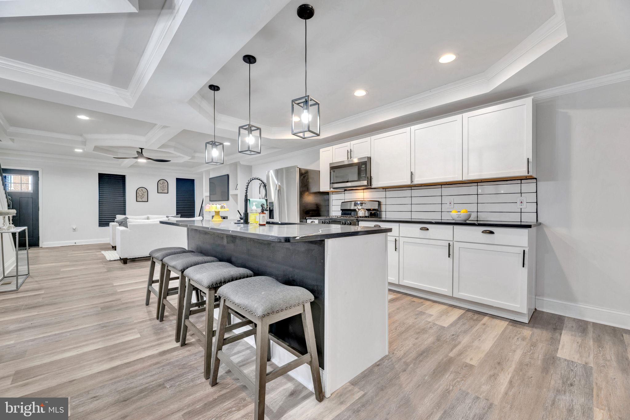 a kitchen with stainless steel appliances kitchen island granite countertop a table chairs and a refrigerator