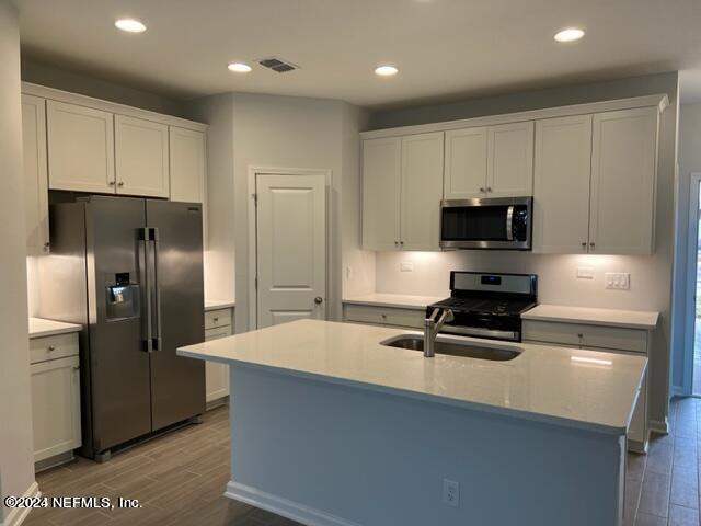 a kitchen with stainless steel appliances a refrigerator a stove a sink and a cabinets