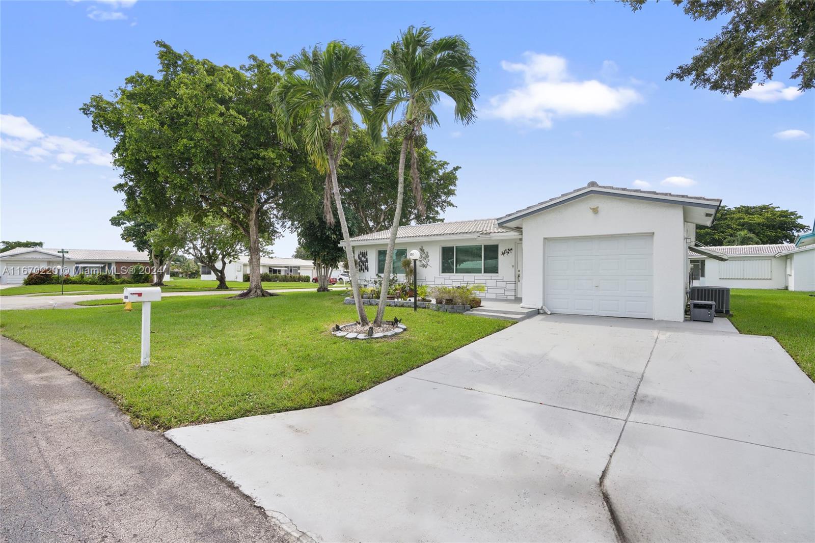 a view of a white house with a yard and palm trees