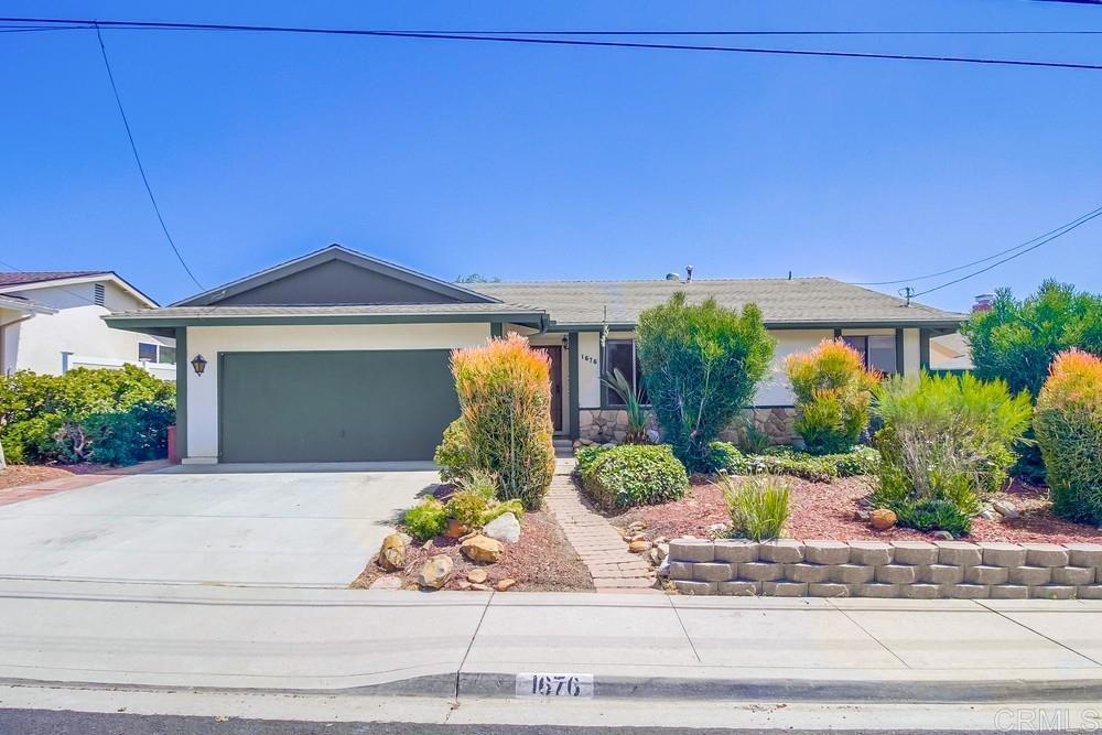 a front view of a house with plants and garage