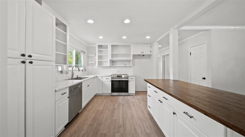 a large kitchen with a stove and white cabinets