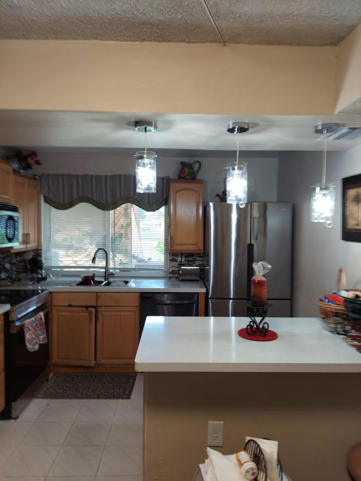 a kitchen with kitchen island granite countertop a sink cabinets and stainless steel appliances