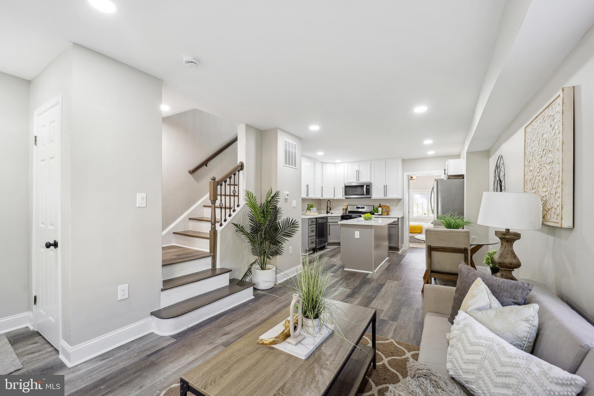 a living room with furniture kitchen view and a wooden floor