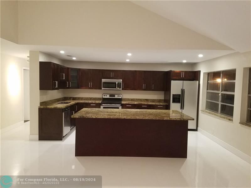 a large kitchen with stainless steel appliances granite countertop a stove and a refrigerator