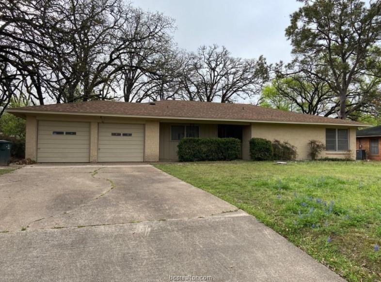 Ranch-style house featuring a garage and a front y