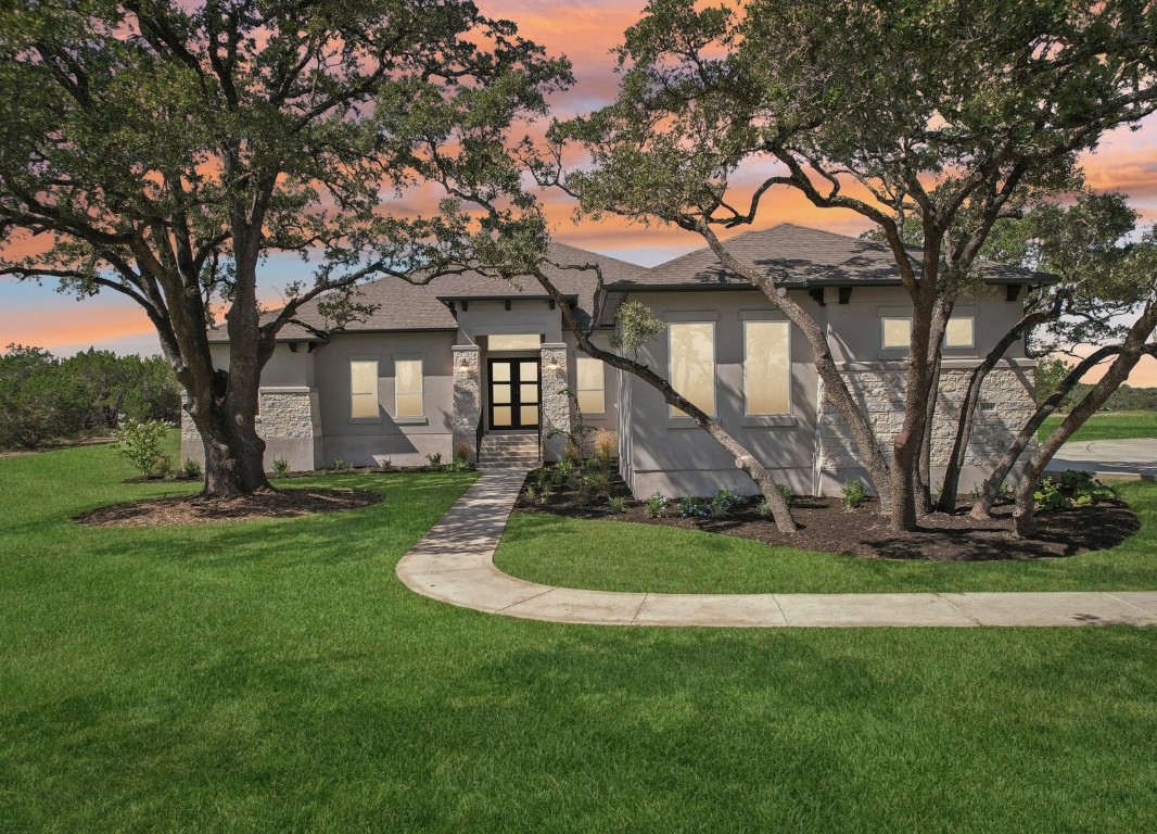 a front view of a house with a garden and trees