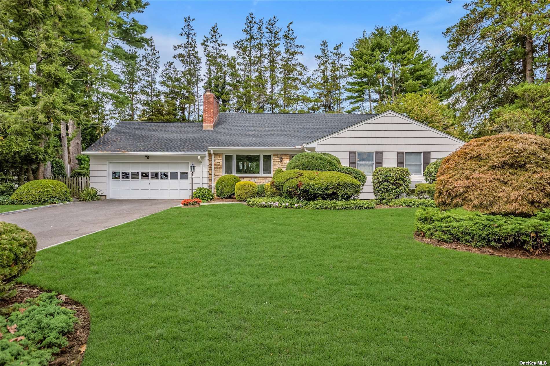 a view of a house with a big yard plants and large trees