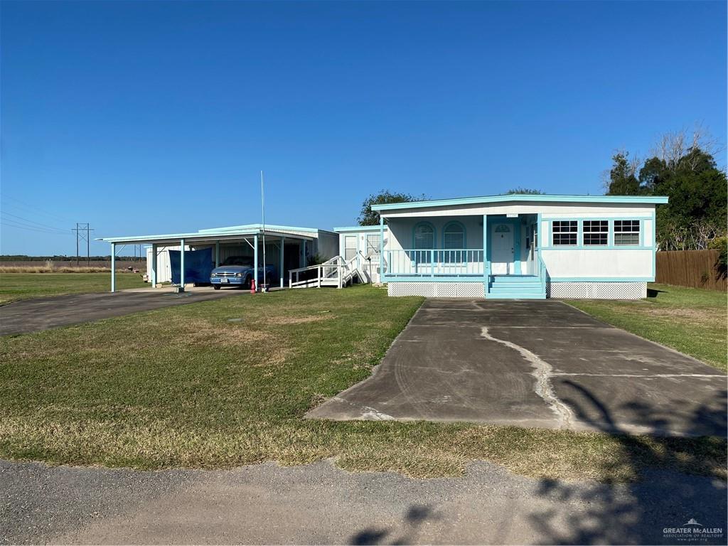 View of front of house with a front lawn, a porch, and a carport