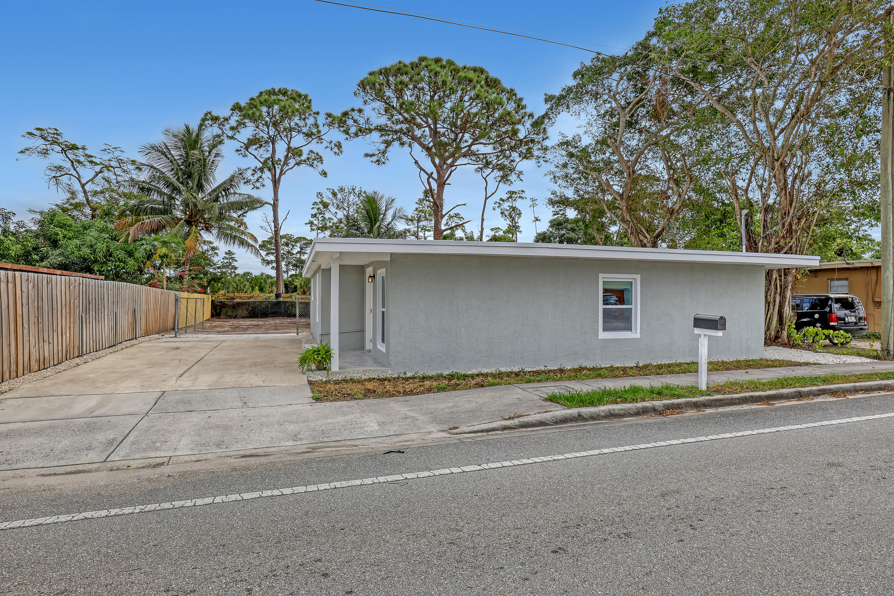 front view of house with a yard and palm trees