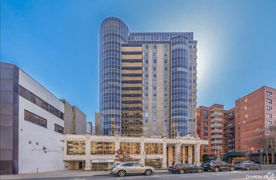 a front view of a building with lot of cars and trees