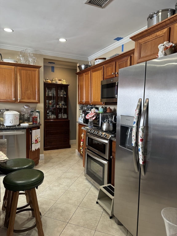 a kitchen with stainless steel appliances kitchen island granite countertop a refrigerator and a stove top oven