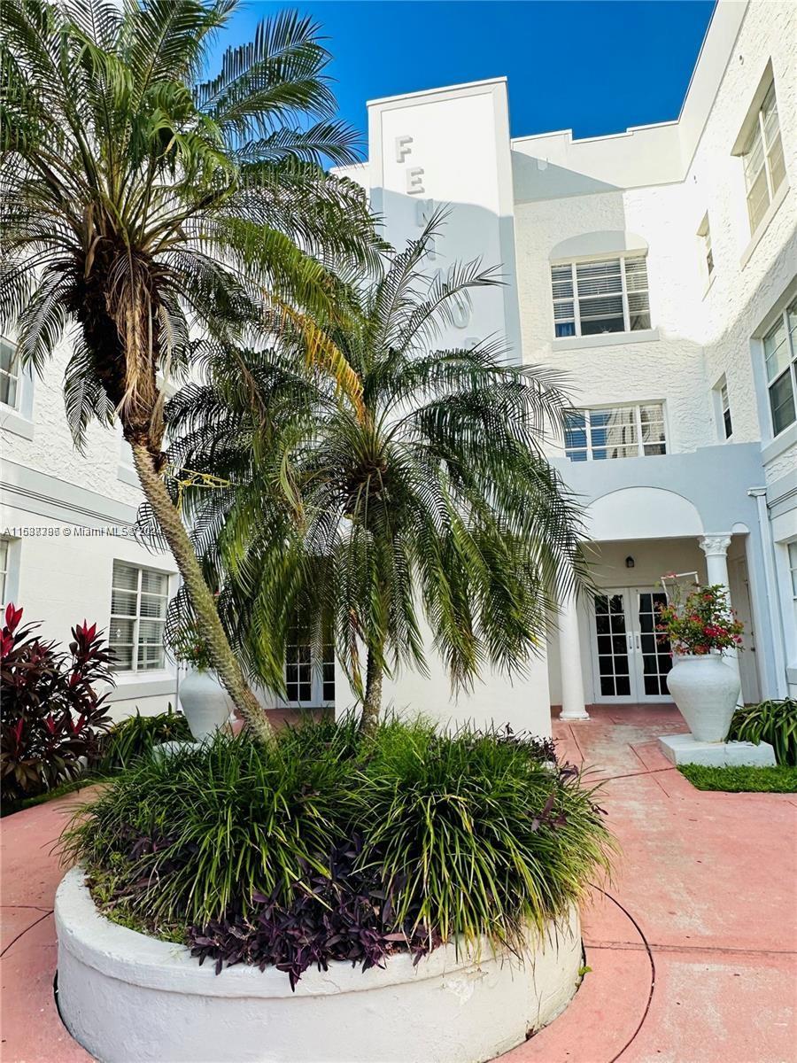 a view of a white house with a yard and potted plants