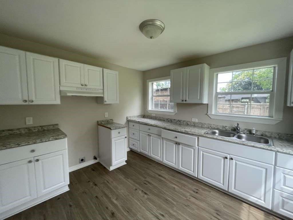 a kitchen with granite countertop white cabinets and a sink