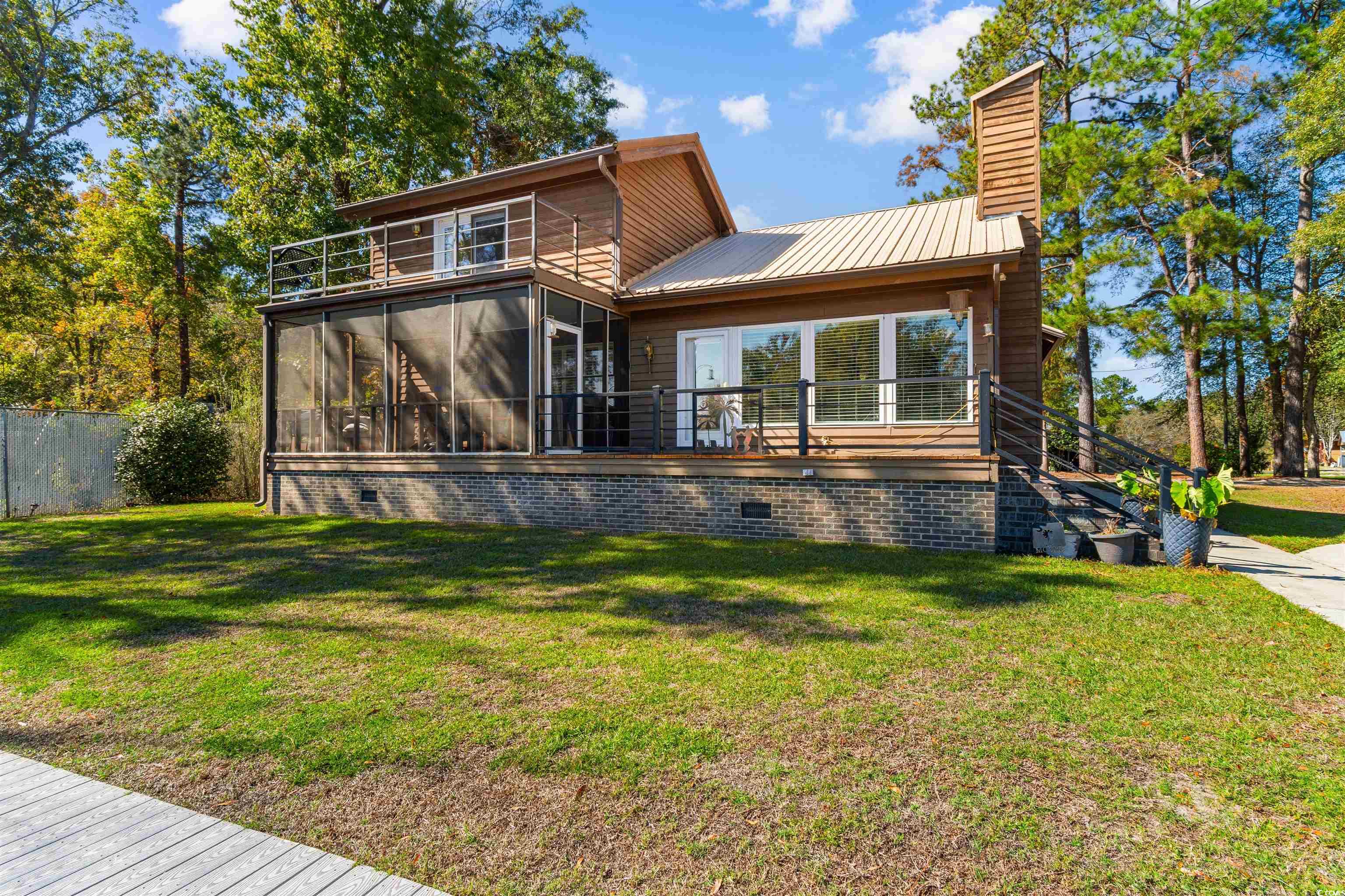 Rear view of house featuring a wooden deck, a yard