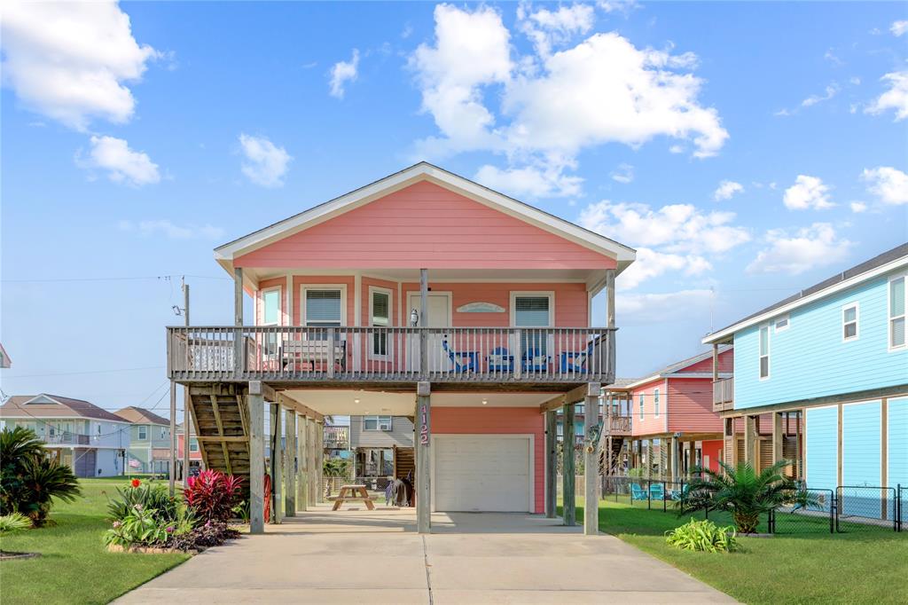 WELCOME TO YOUR VIBRANT BEACH RETREAT! THIS ELEVATED CORAL-COLORED HOME BOASTS A CHARMING WRAP-AROUND PORCH, PERFECT FOR RELAXING AND SOAKING IN THE COASTAL BREEZE.