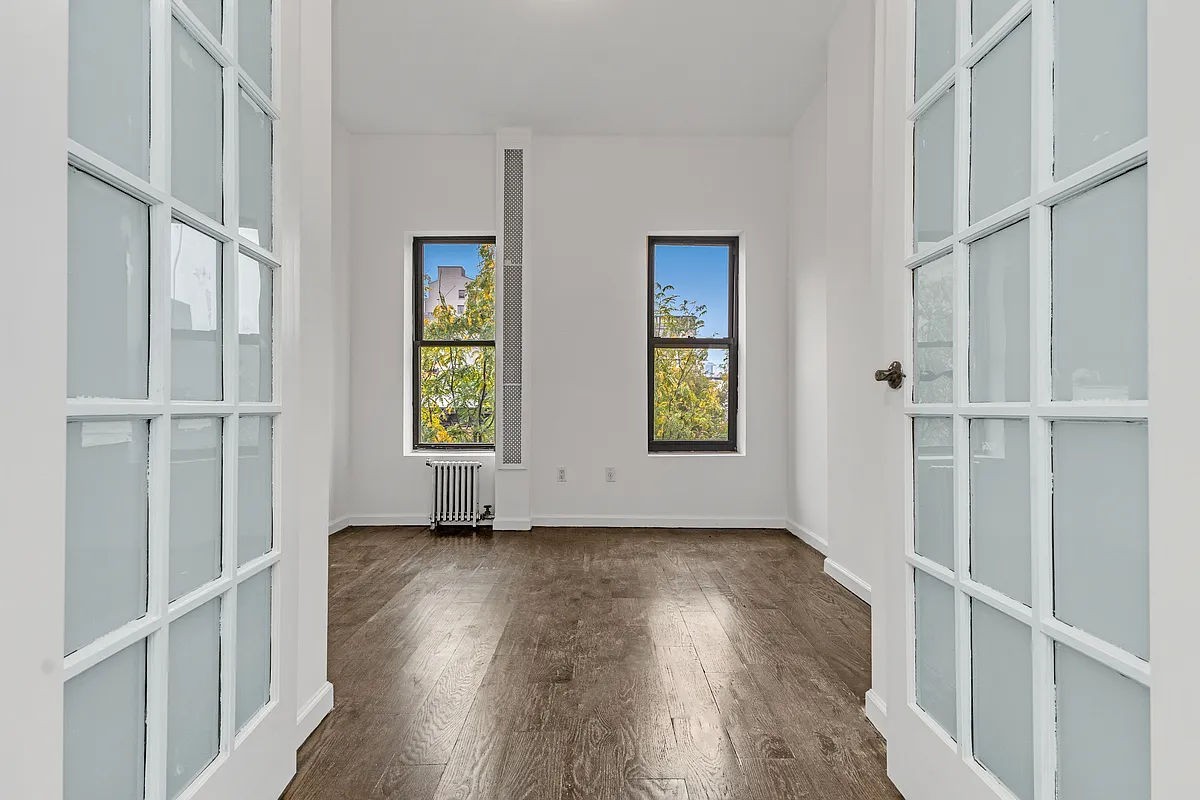 an empty room with wooden floor and windows