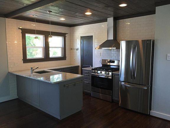 a kitchen with stainless steel appliances granite countertop a refrigerator a sink and a stove