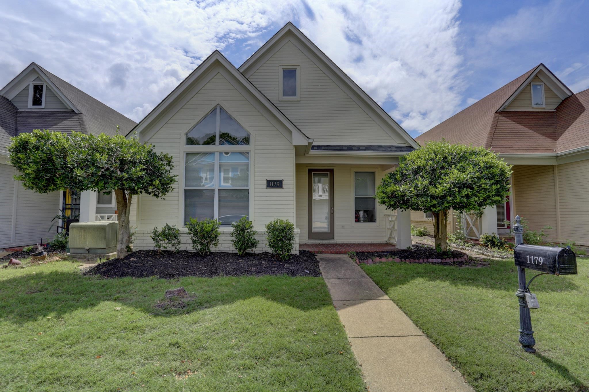 a front view of a house with a yard and trees