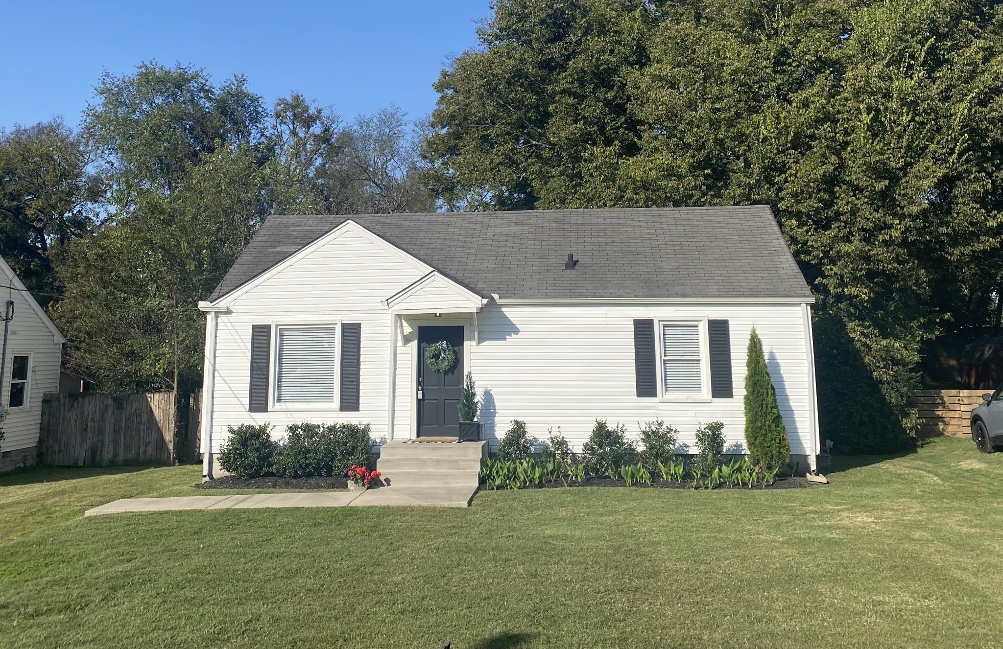 front view of house with a yard and trees all around