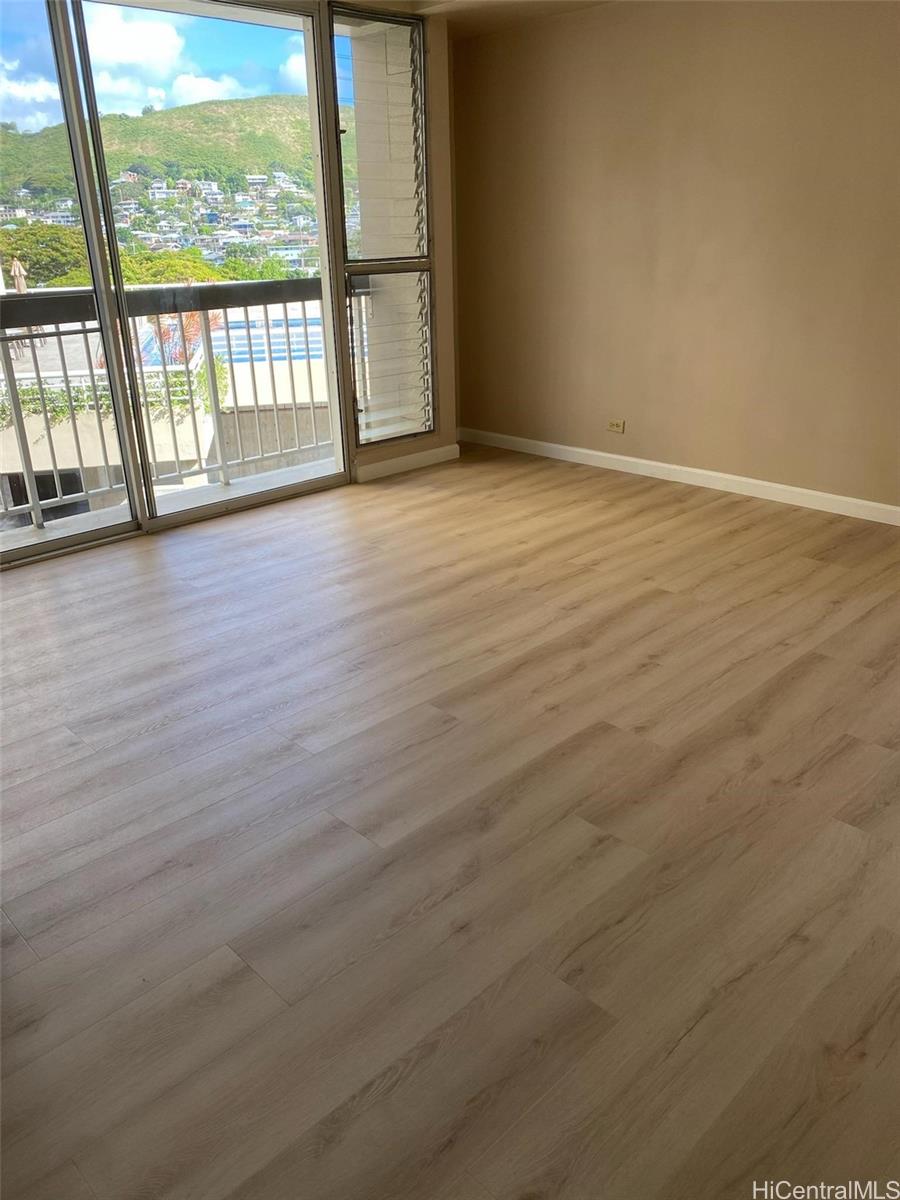 a view of an empty room with wooden floor and a window