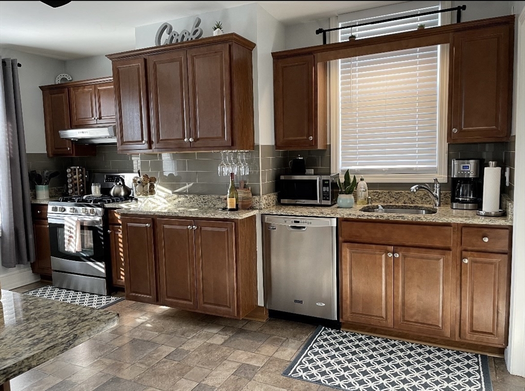 a kitchen with stainless steel appliances granite countertop a stove a sink and a microwave