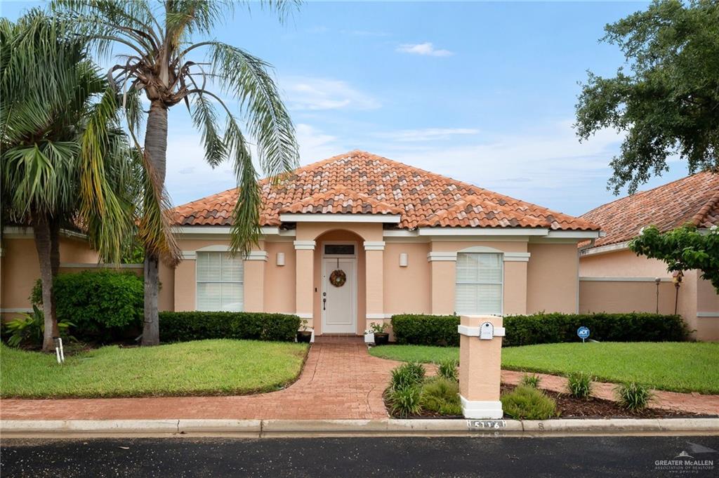 a front view of a house with a yard and palm trees