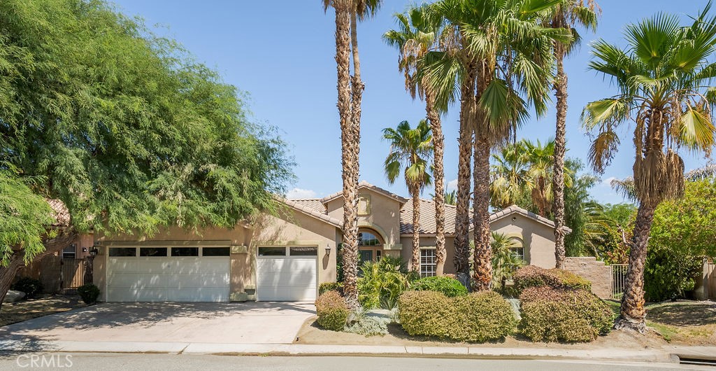 a front view of a house with a yard and palm trees