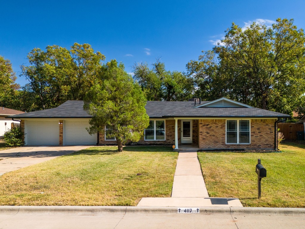 a front view of house with yard and trees in the background