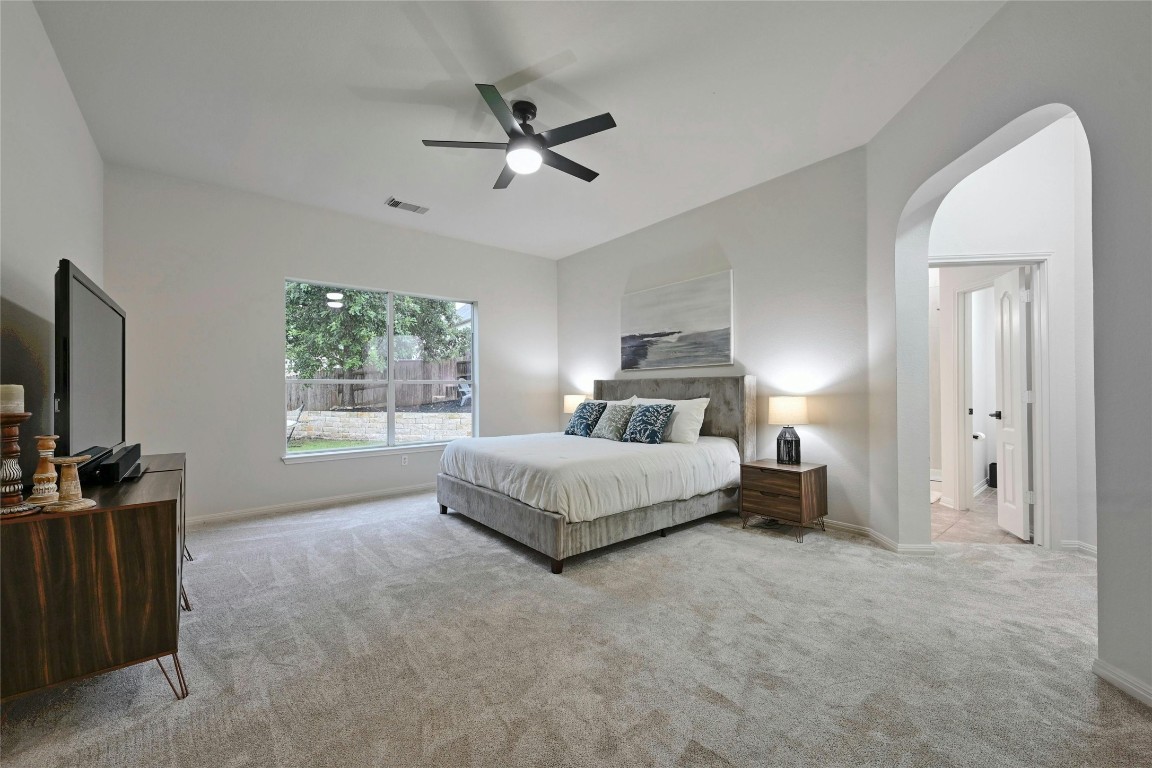 Kick back and relax in your grandiose Owner's Suite featuring plush carpet flooring, high ceilings, and a modern ceiling fan.