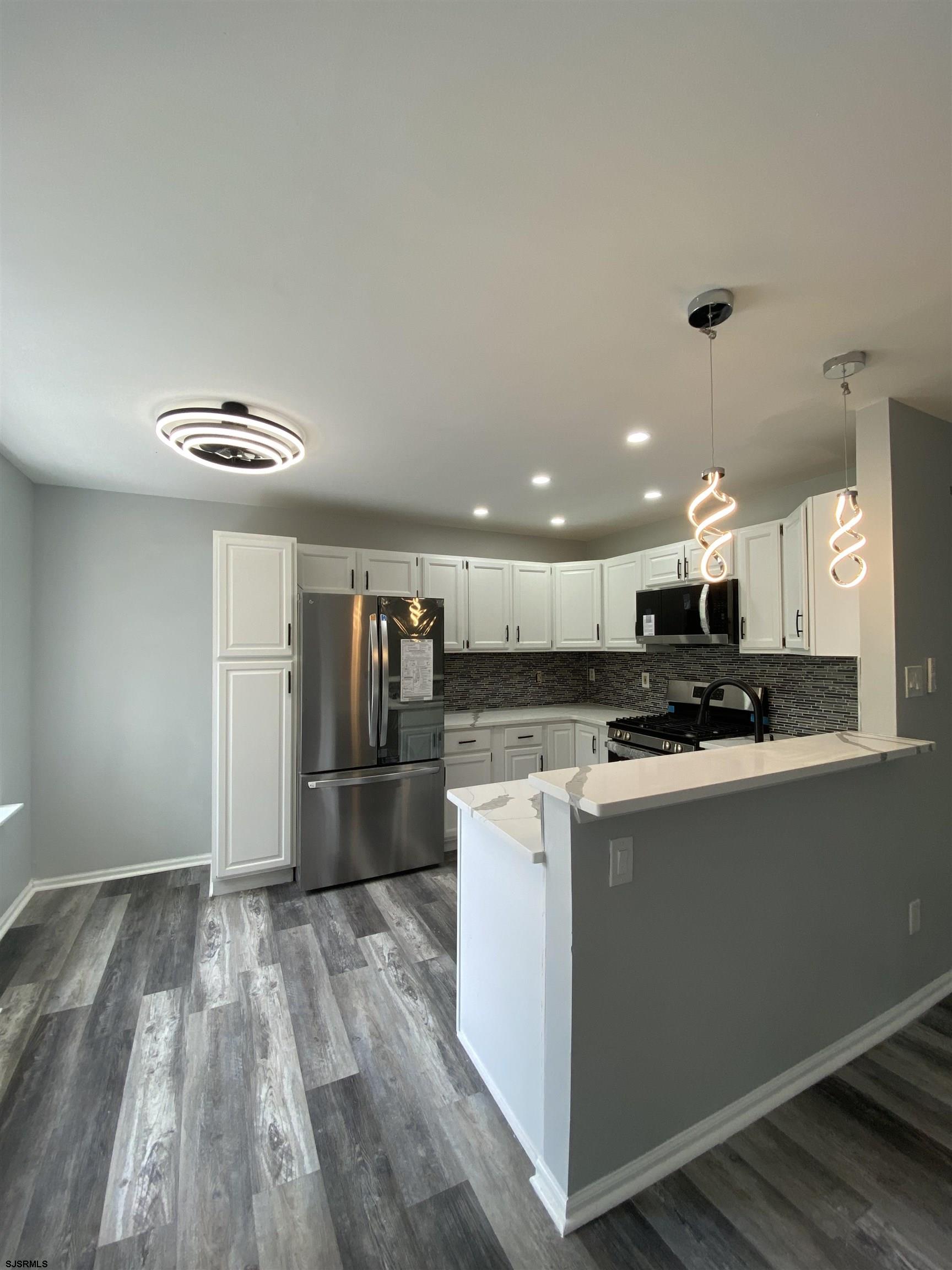 a kitchen with kitchen island a refrigerator a stove top oven and a sink