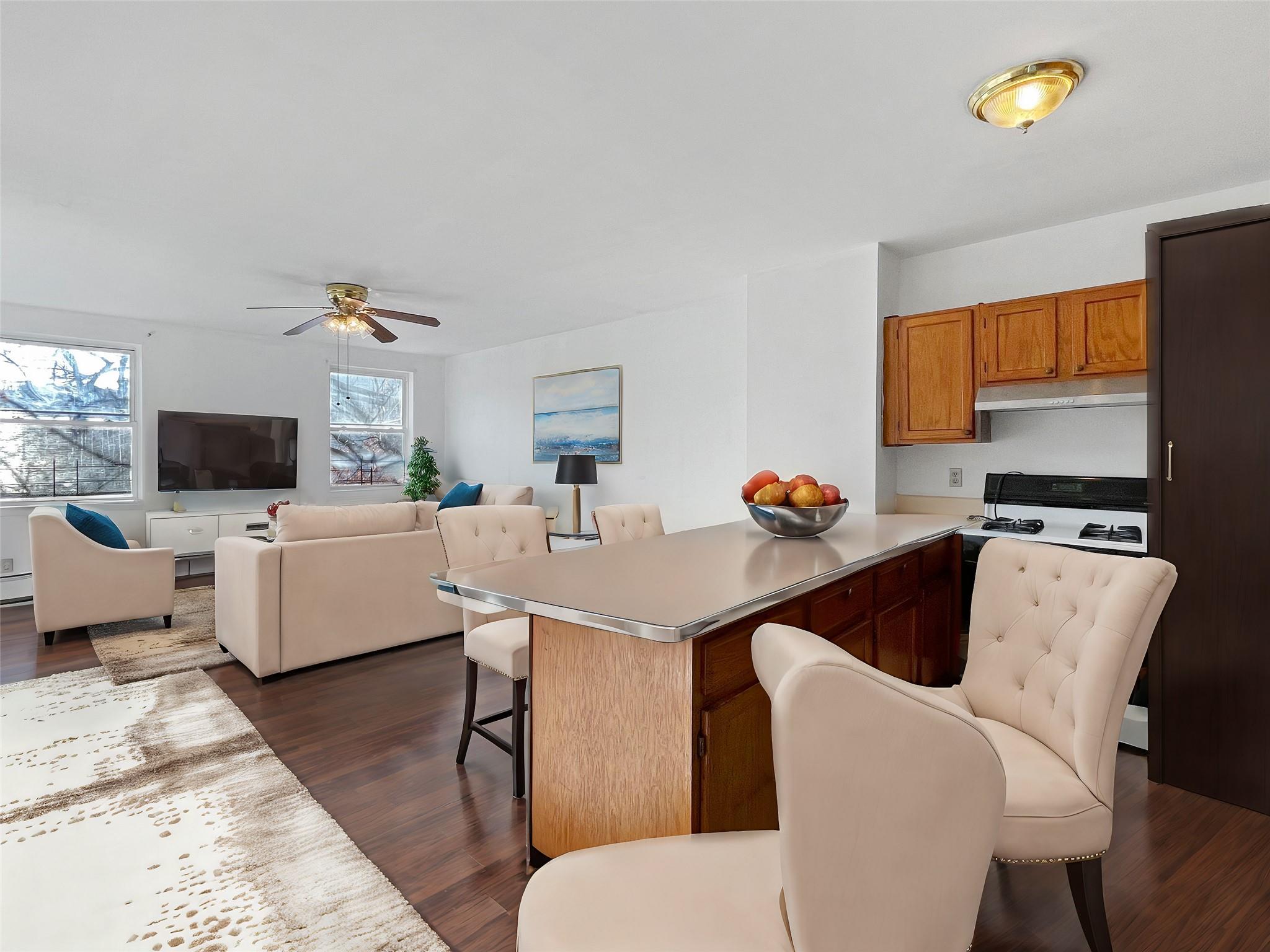 Kitchen with a breakfast bar, stove, dark wood-type flooring, ceiling fan, and a kitchen island