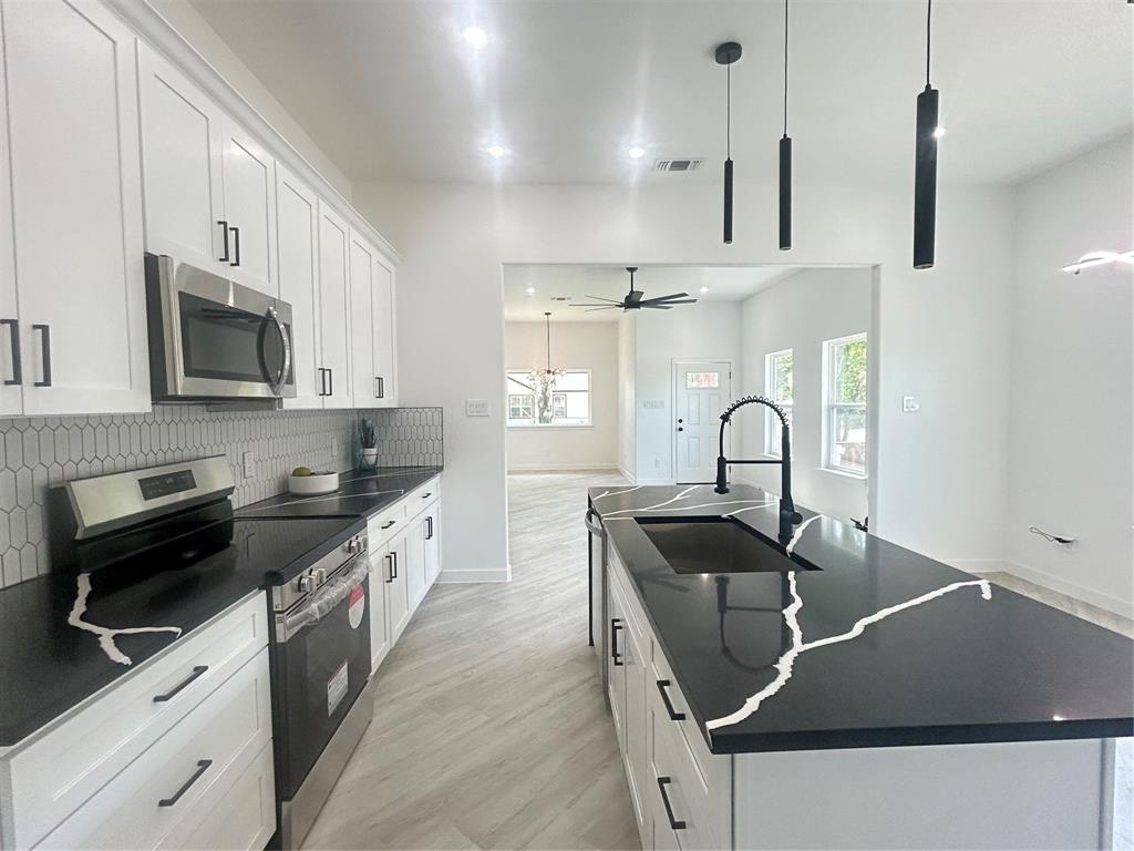 a kitchen with granite countertop a sink a stove and cabinets