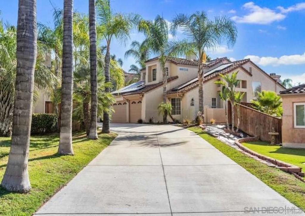 a view of a house with a yard and palm trees