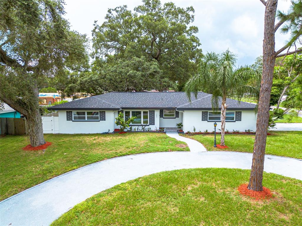 a view of a house with a big yard plants and large trees