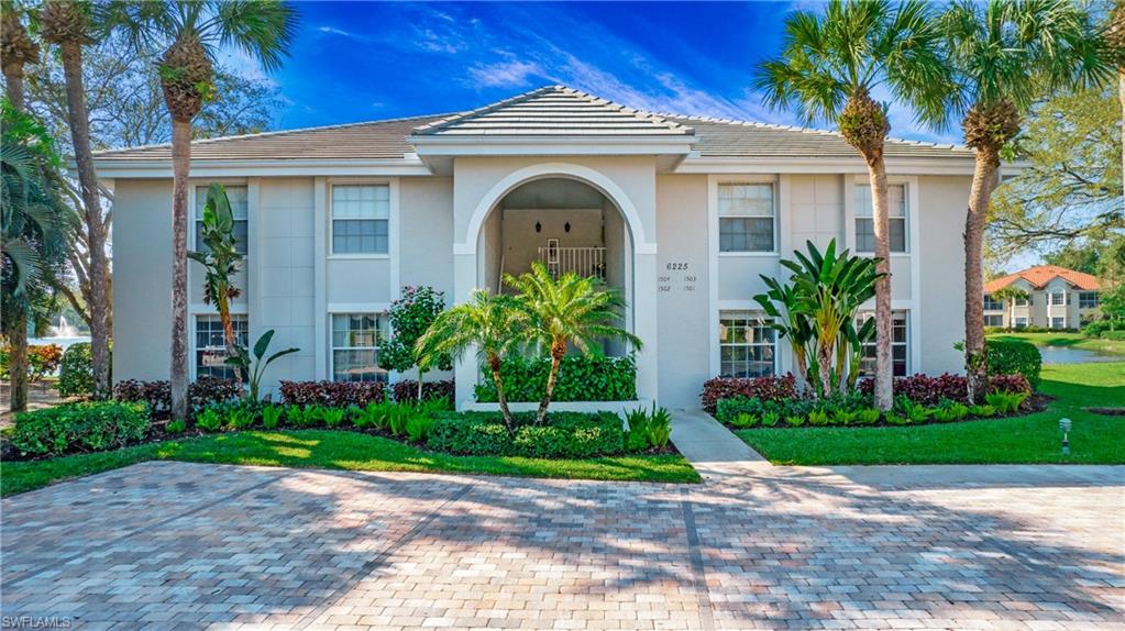 a view of a house with a small yard and palm trees