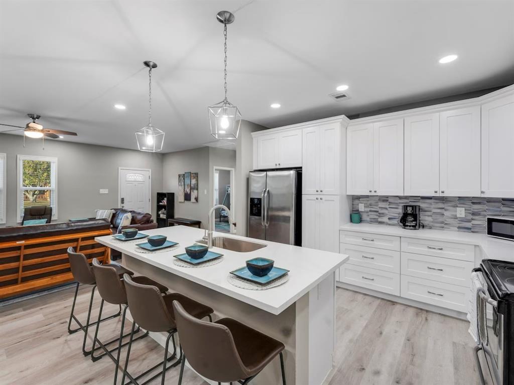 a kitchen with a dining table chairs refrigerator and microwave