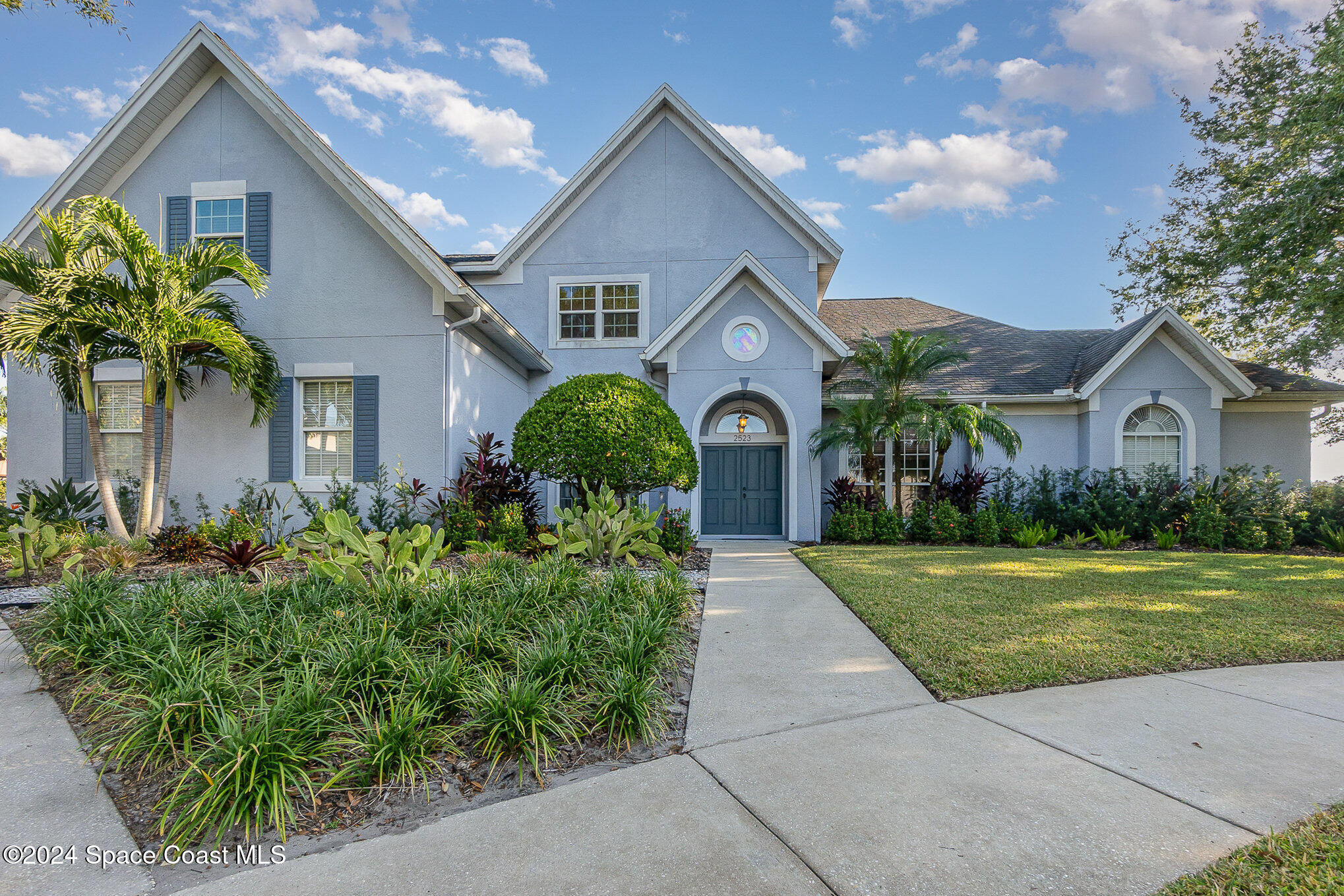 a front view of a house with a yard and potted plants