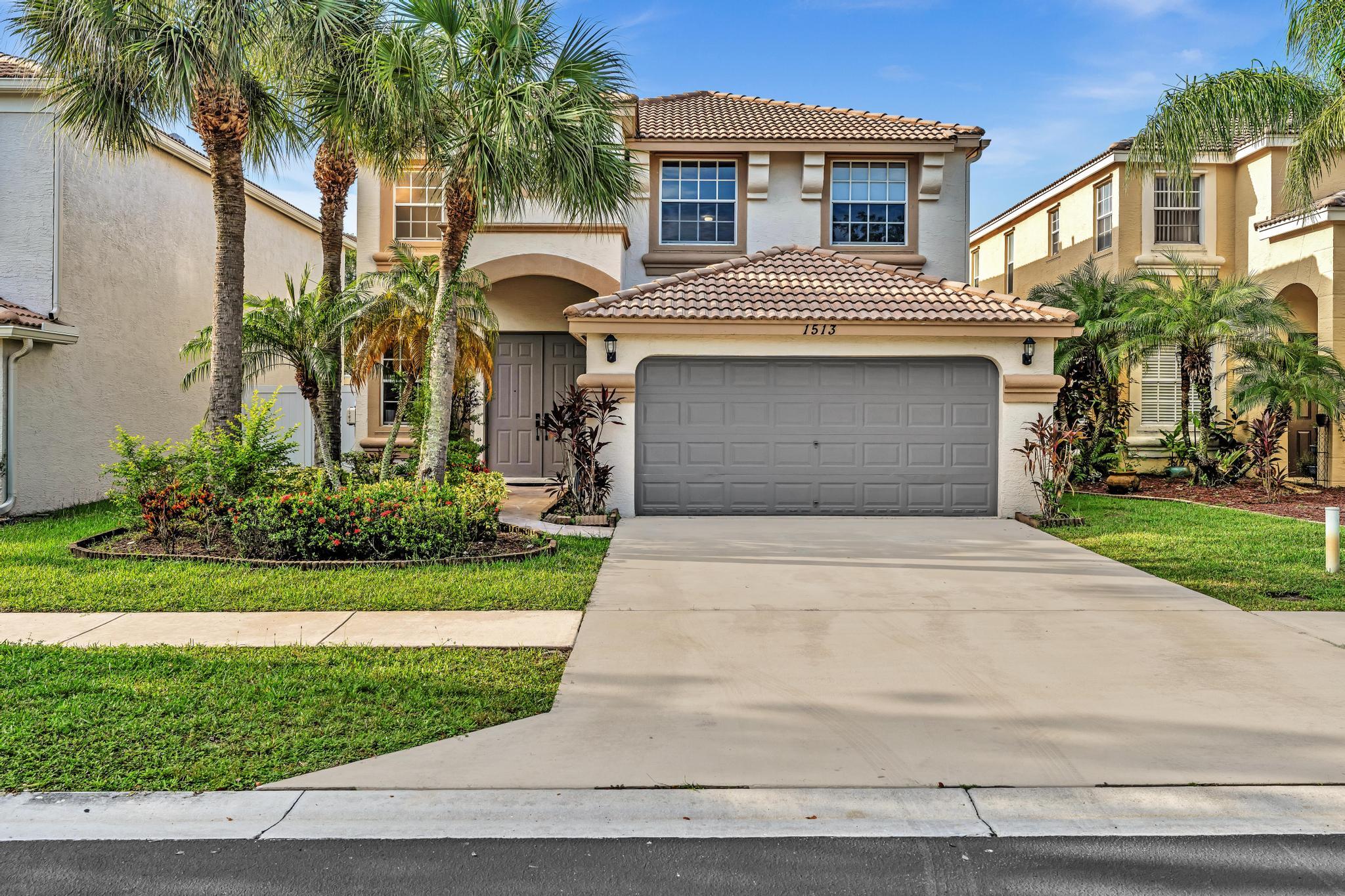 a front view of a house with a garden and palm trees