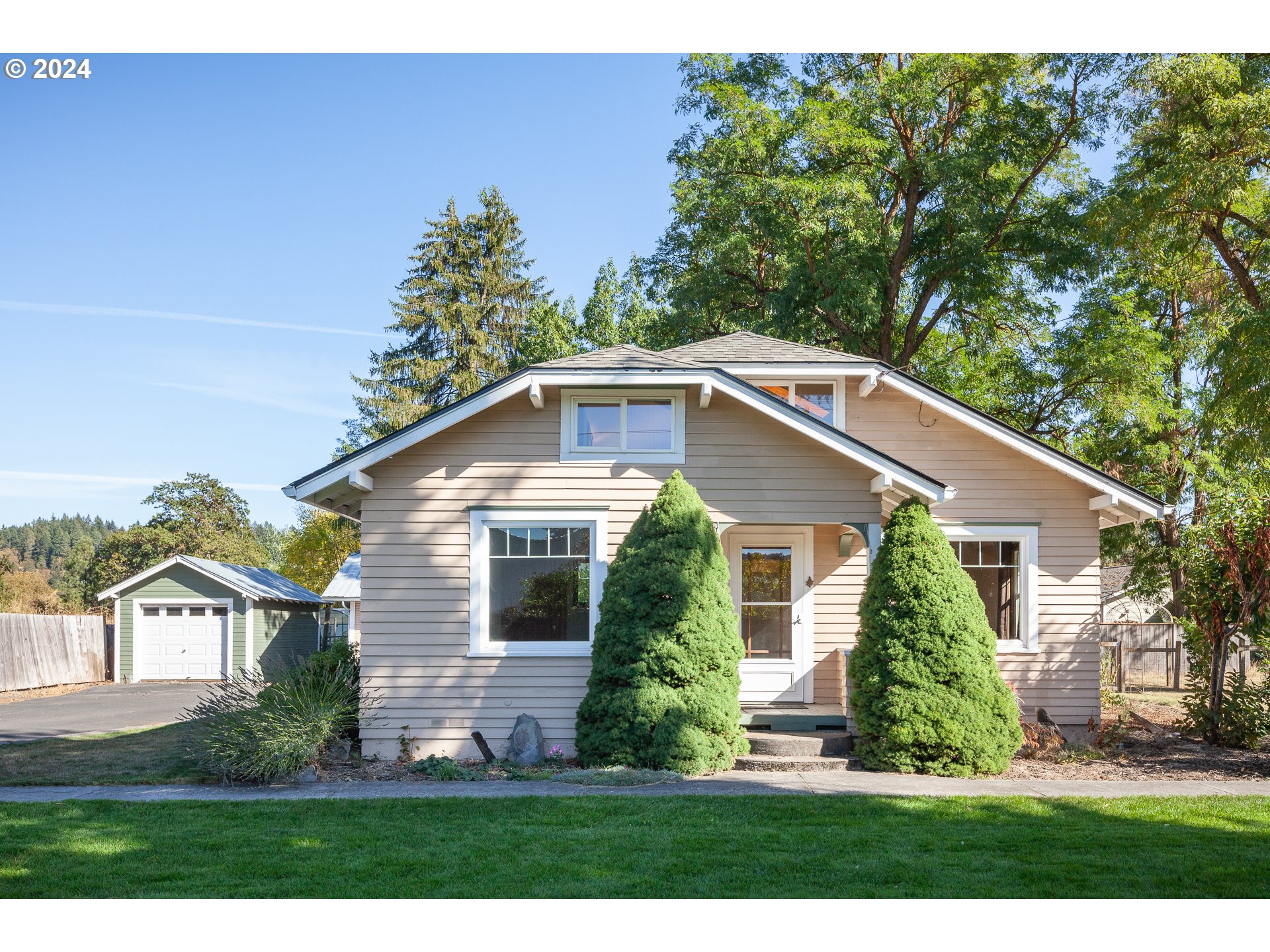 a front view of a house with a yard and potted plants