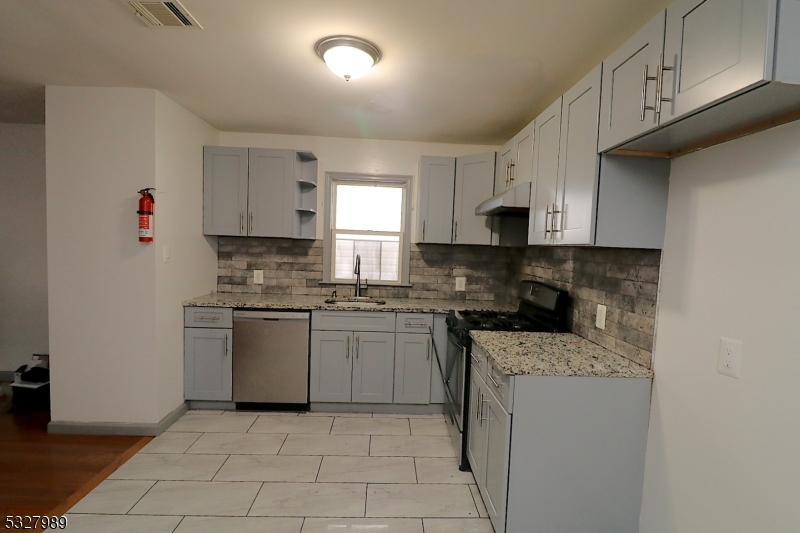 a kitchen with granite countertop white cabinets sink and stainless steel appliances